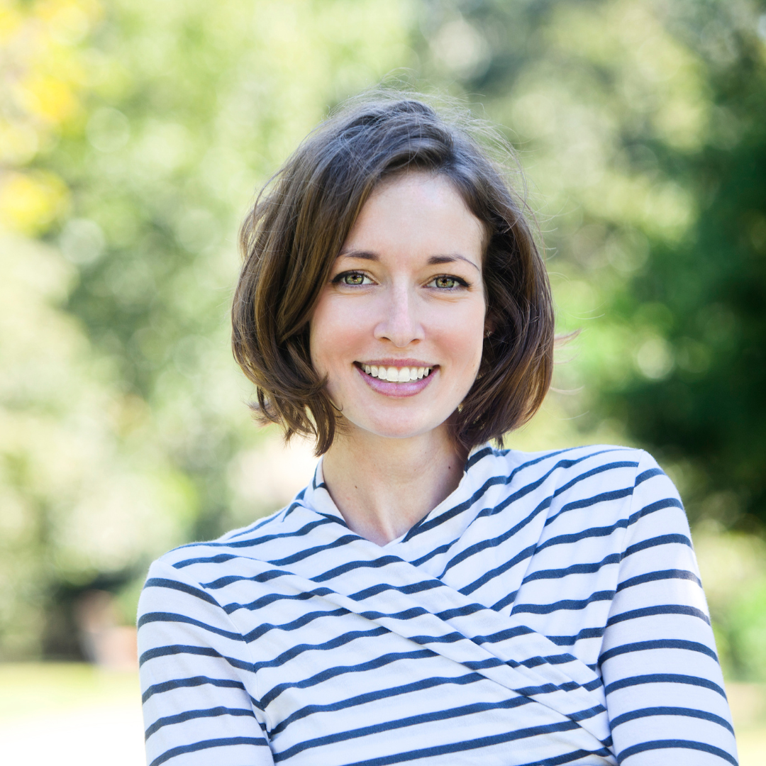 Smiling woman with clear aligners holding a green apple